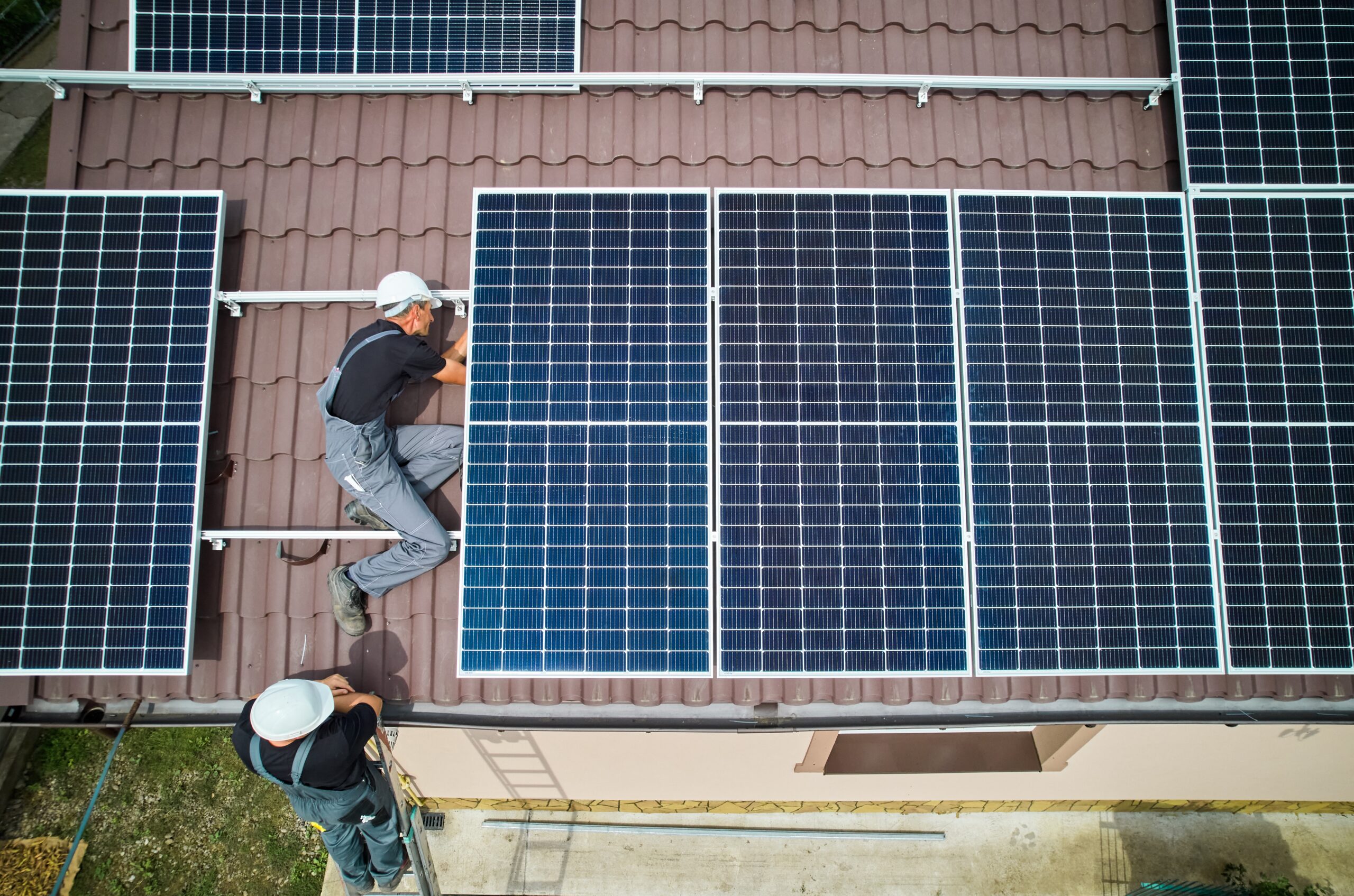 Arbeiter montieren Solarpanelen auf einem Dach